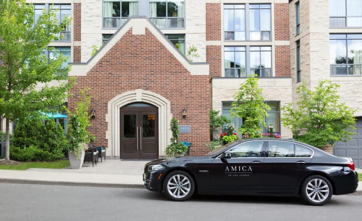 OnTheAvenue-home-exterior_shot_of_building_at_the_entrance_with_amica_branded_black_car_parked_infront Exterior shot of Amica On The Avenue's entrance area, with an Amica branded black car parked in front of the residence.