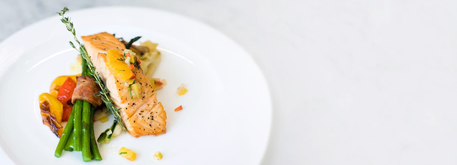 Amica Dining Panel Fade Left Amica senior living residence salmon and asparagus entree.