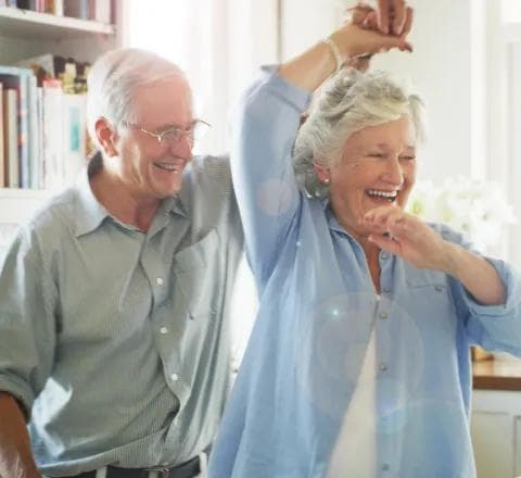 Amica Senior Couple Dancing Laughing An elderly couple laughing and dancing together indoors