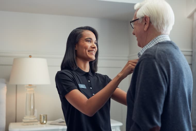 Lifestyle shoot - Caregiver Helping Resident with Buttons 1 Female caregiver assisting male resident with shirt buttons in suite